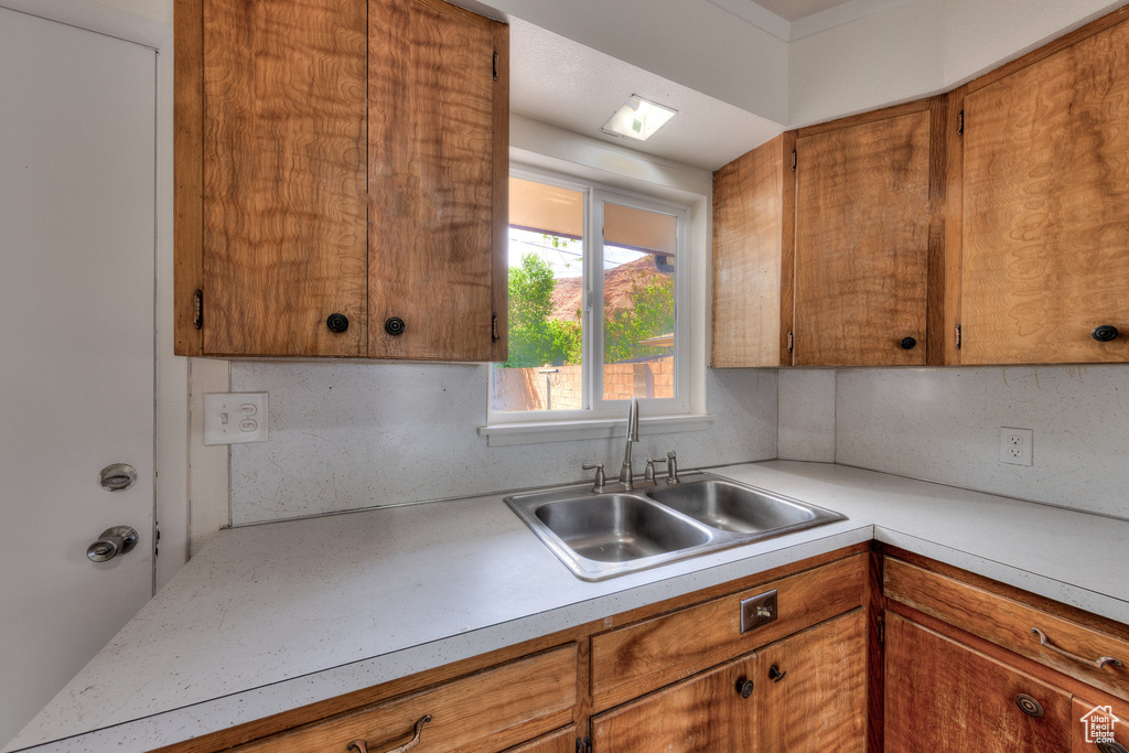 Kitchen featuring light countertops, brown cabinetry, and a sink
