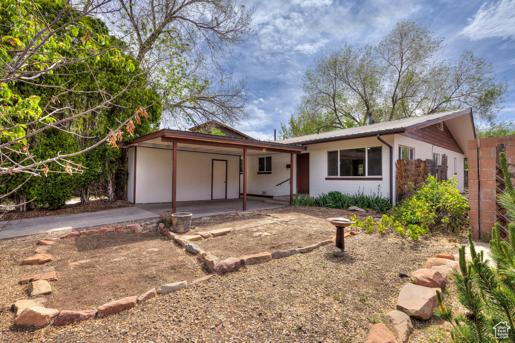 Single story home with concrete driveway, metal roof, concrete block siding, and a carport