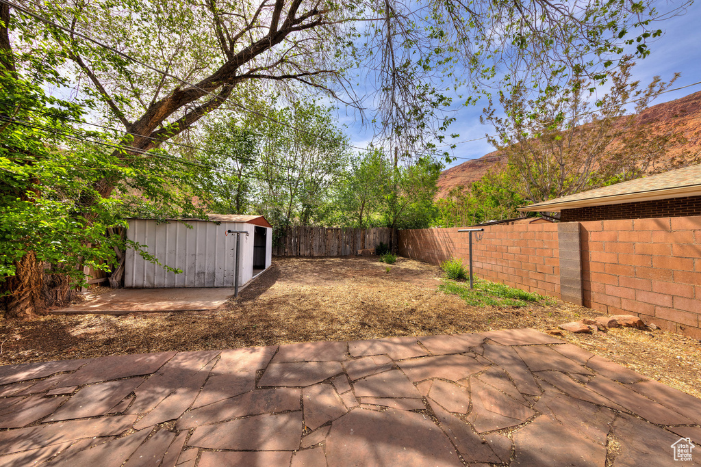 View of patio / terrace with an outdoor structure, a fenced backyard, and a shed