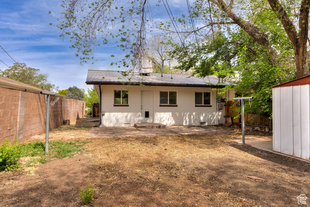 Back of house featuring an outbuilding, metal roof, a fenced backyard, and a patio area