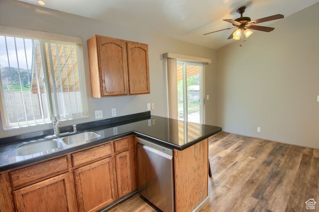 Kitchen featuring stainless steel dishwasher, a peninsula, a sink, and light wood-style flooring