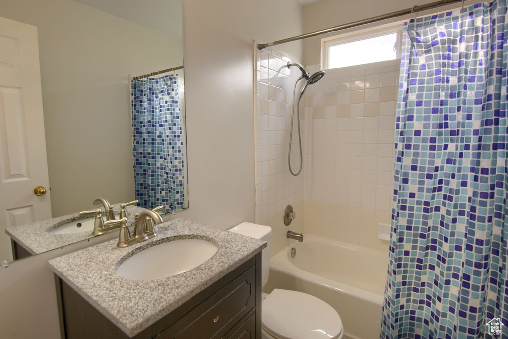 Full bathroom with vanity, shower / bath combo, and toilet