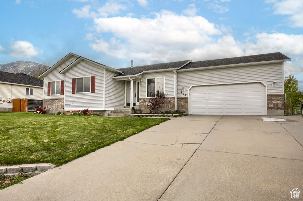 Ranch-style home with driveway, brick siding, fence, a front lawn, and an attached garage