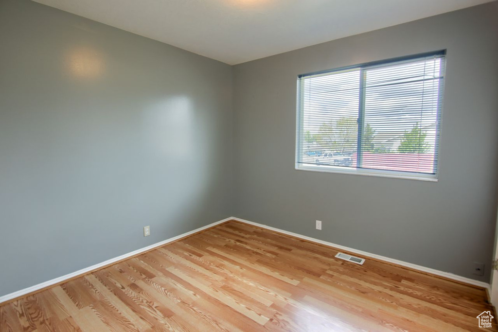 Empty room featuring baseboards, wood finished floors, and visible vents