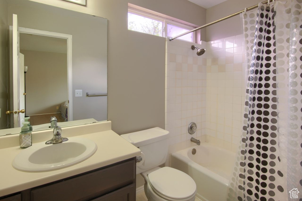 Full bathroom with vanity, shower / bathtub combination with curtain, and toilet