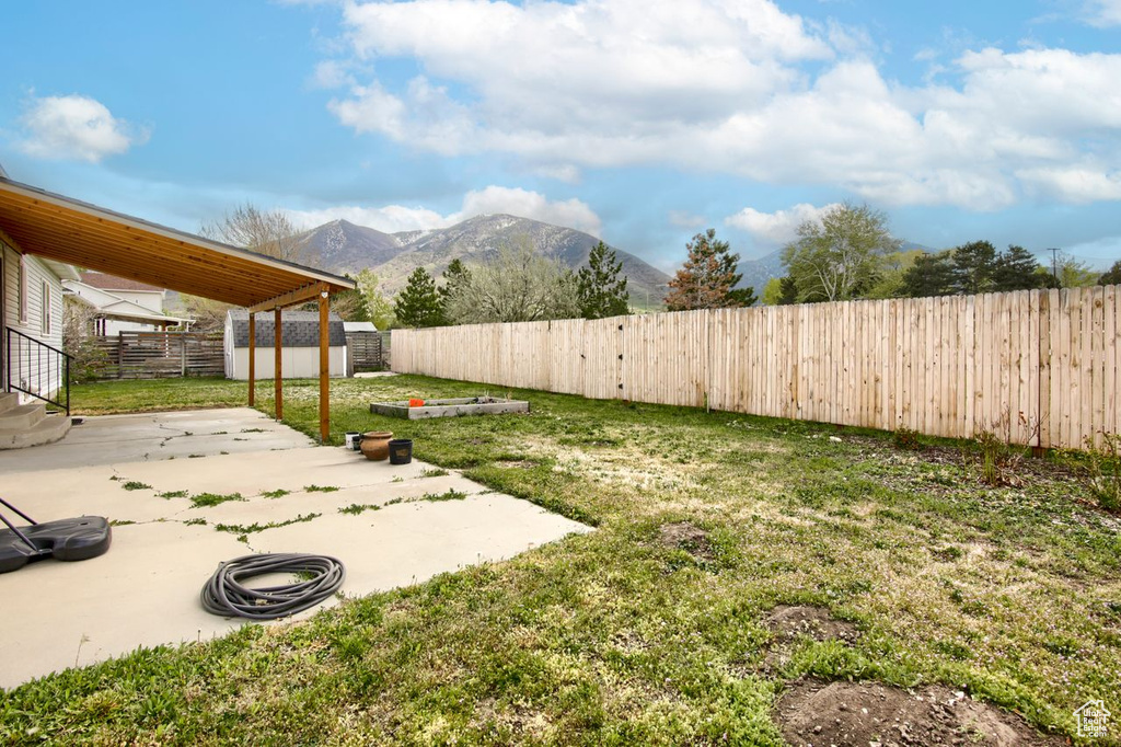 View of yard featuring an outdoor structure, a mountain view, a fenced backyard, a patio, and a storage unit