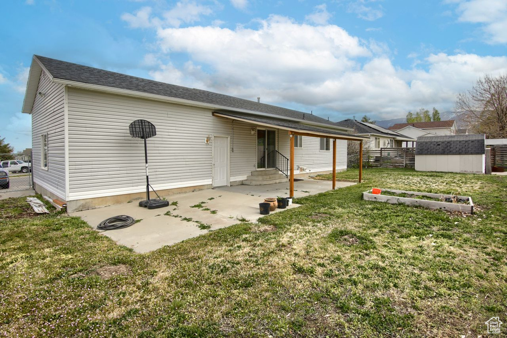 Rear view of property featuring fence, a storage shed, entry steps, a patio, and a yard