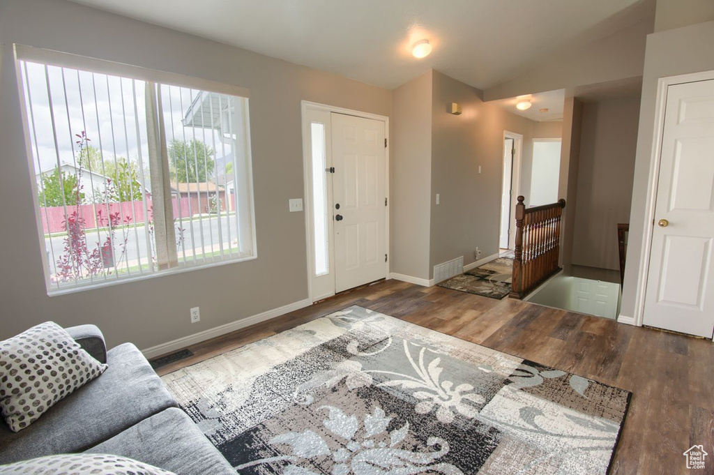 Entryway with visible vents, baseboards, lofted ceiling, and wood finished floors