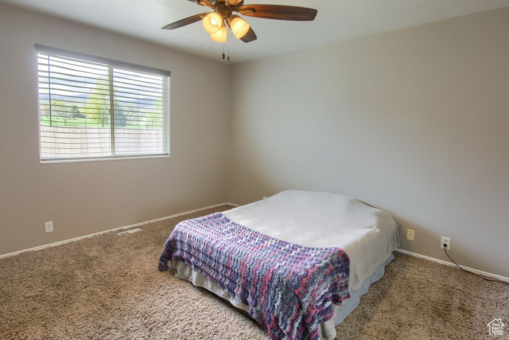 Carpeted bedroom featuring baseboards, ceiling fan, and visible vents