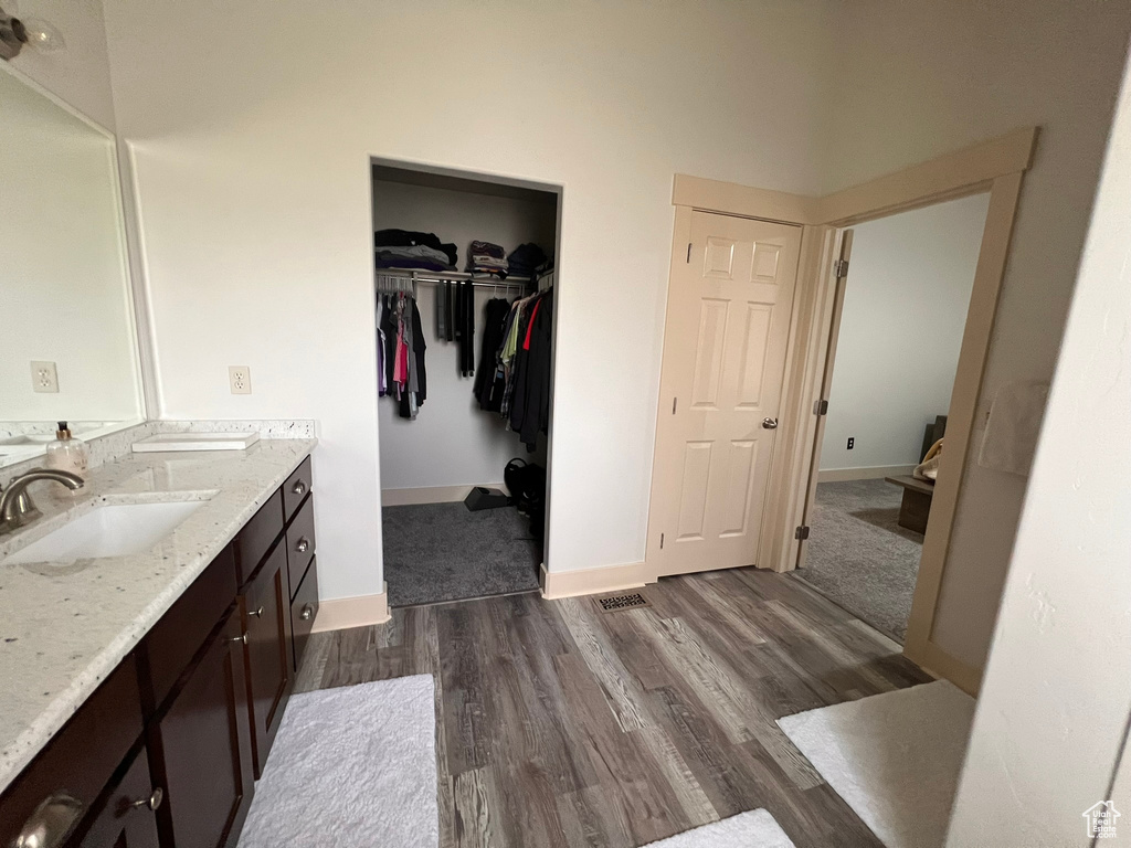 Bathroom featuring baseboards, vanity, wood finished floors, and a walk in closet