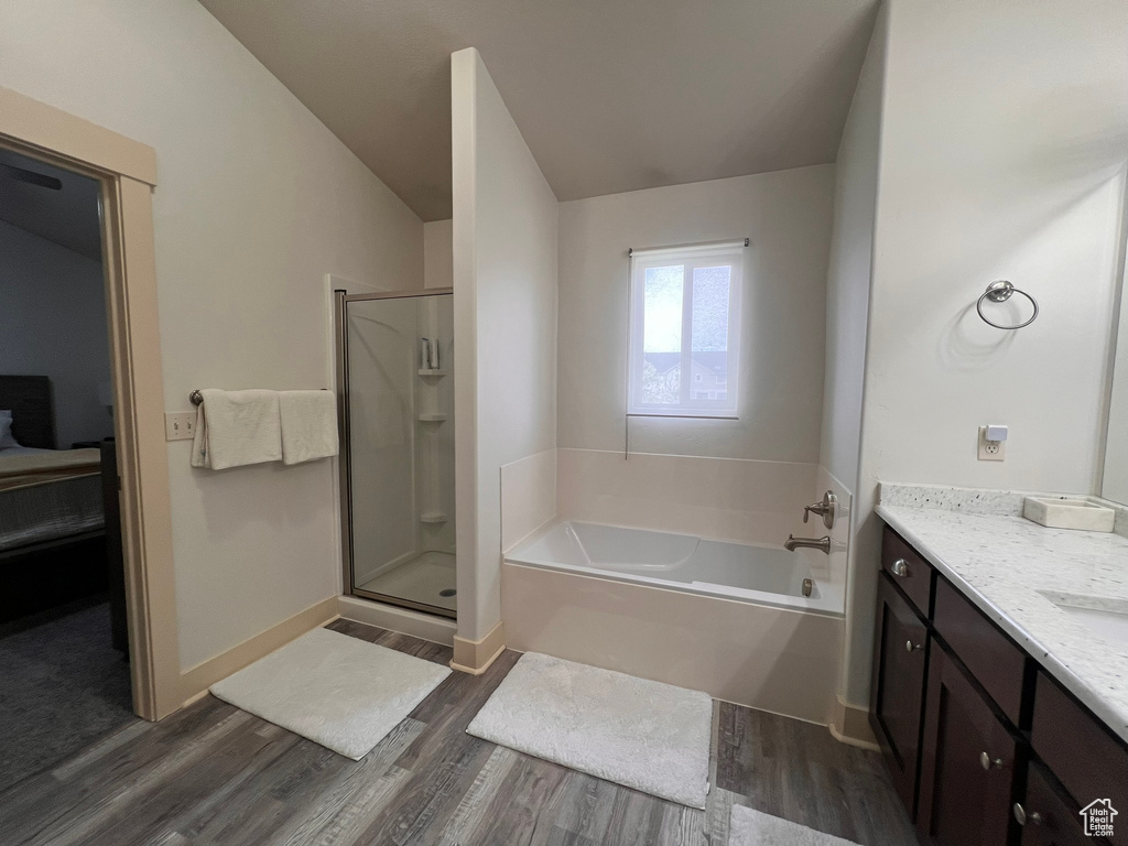 Bathroom with vanity, baseboards, wood finished floors, a bath, and a stall shower