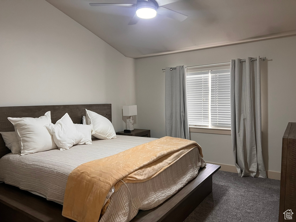 Carpeted bedroom with ceiling fan and vaulted ceiling