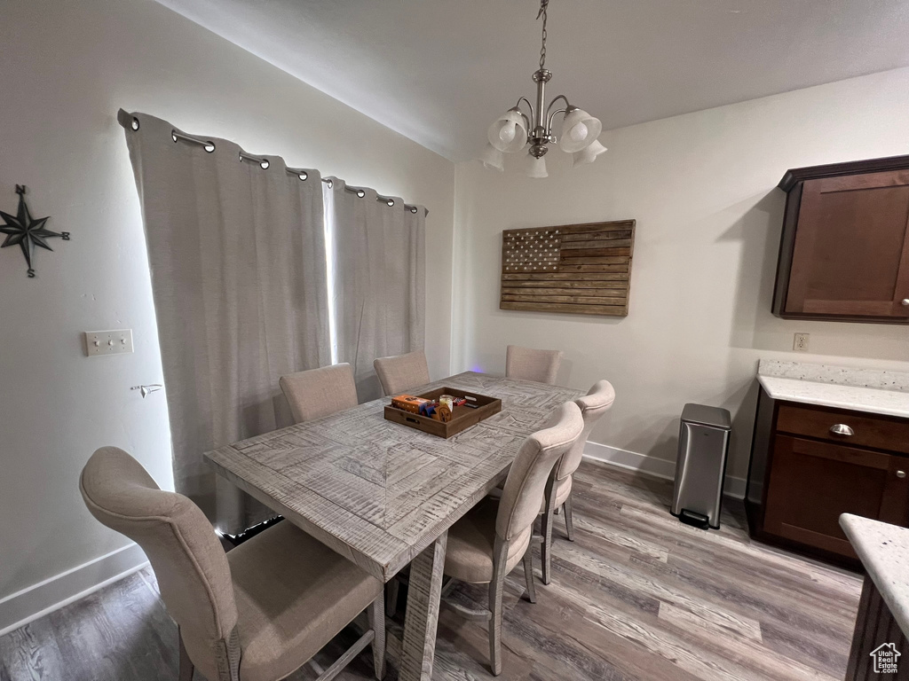 Dining room with baseboards, a chandelier, and light wood finished floors