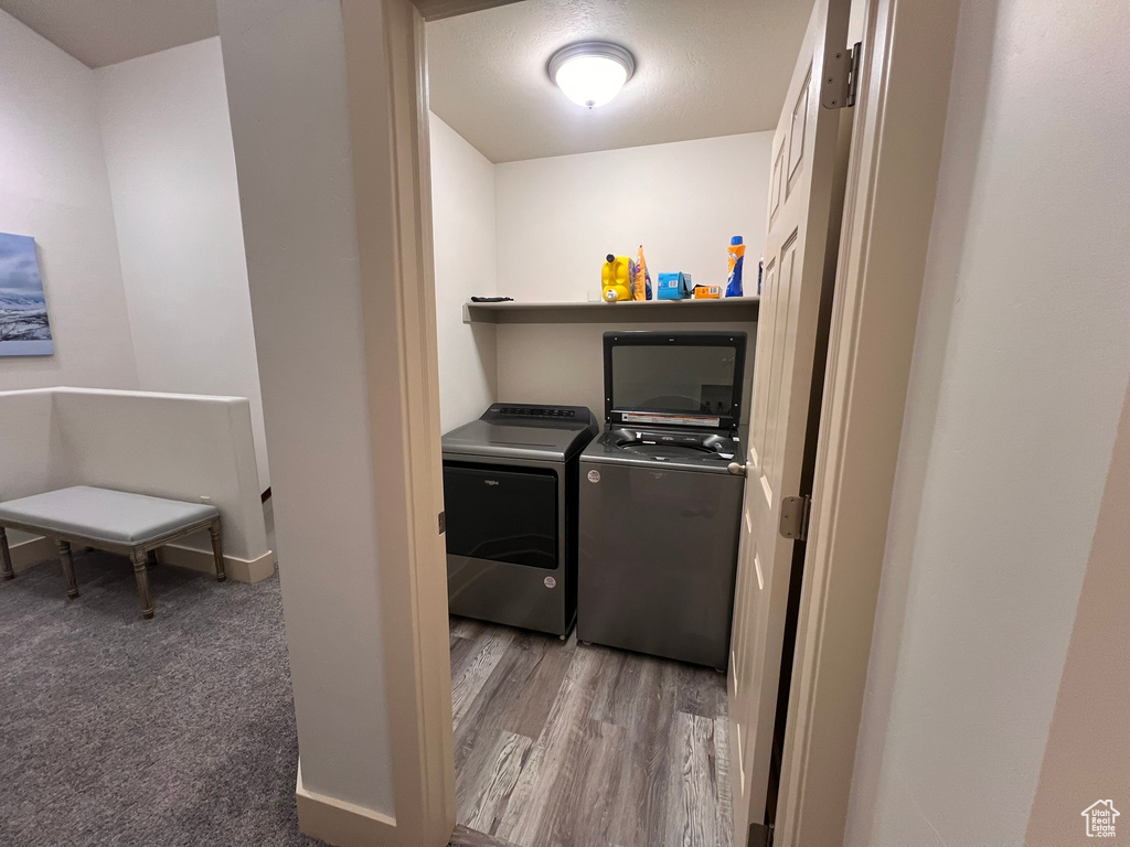 Washroom with independent washer and dryer, laundry area, baseboards, and wood finished floors