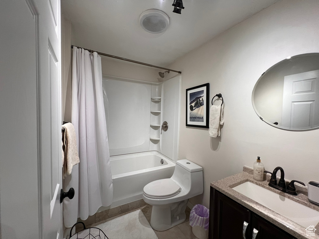 Full bath with toilet, tile patterned floors, shower / bath combination with curtain, and vanity