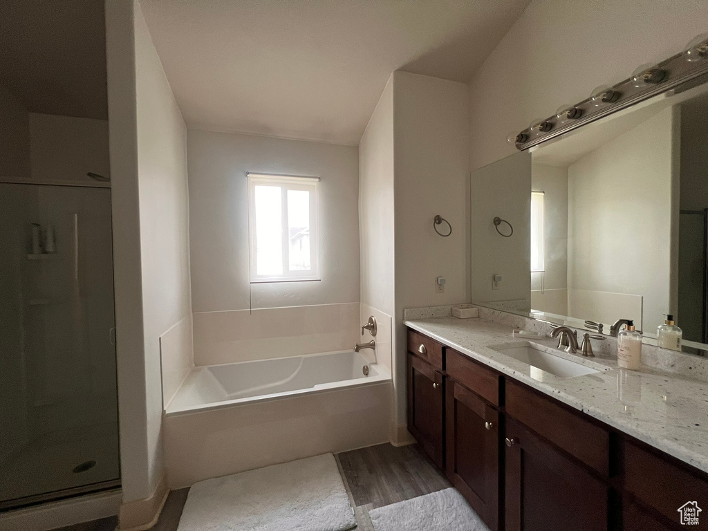 Full bathroom with a garden tub, vanity, wood finished floors, and a shower stall