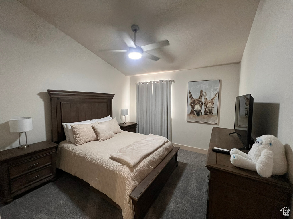 Bedroom with a ceiling fan, baseboards, vaulted ceiling, and dark carpet
