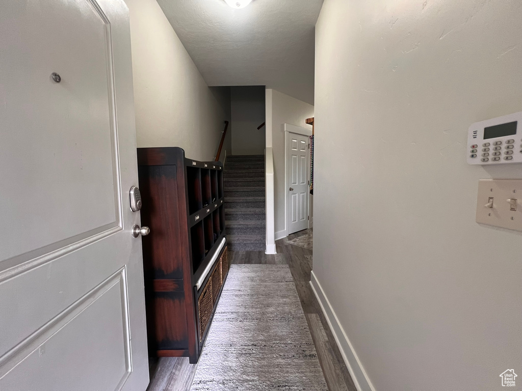 Hallway featuring baseboards, stairs, and wood finished floors