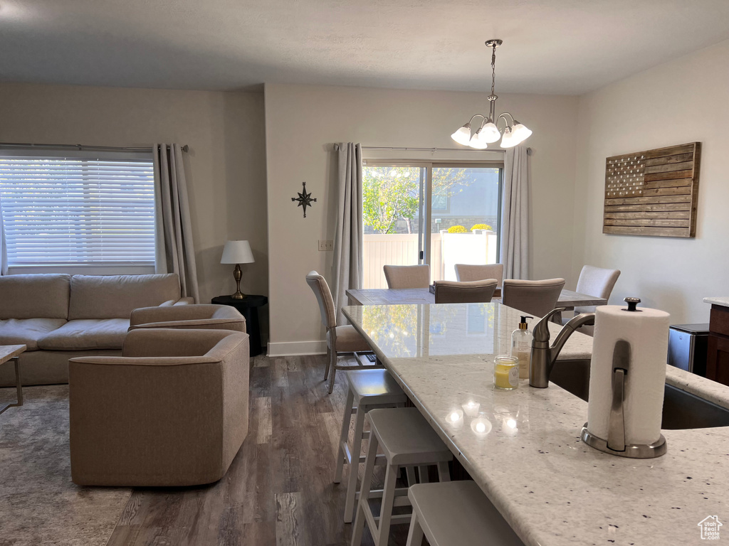 Dining area with baseboards, a chandelier, and dark wood-style floors