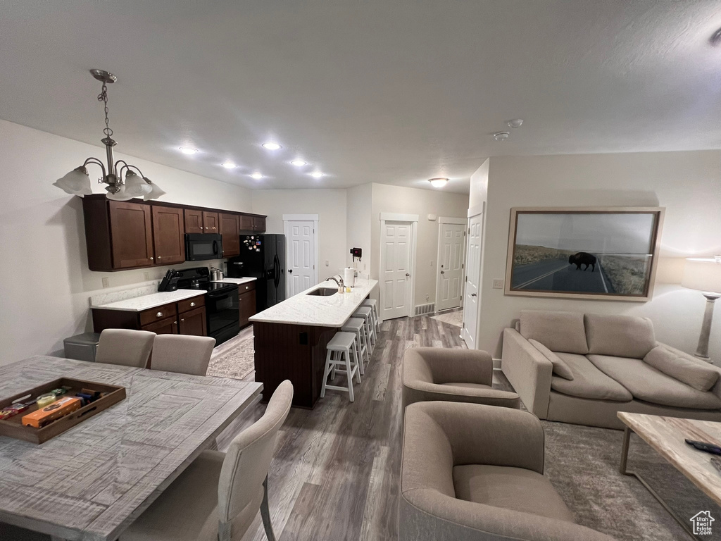 Living room featuring dark wood-type flooring, baseboards, a notable chandelier, and visible vents