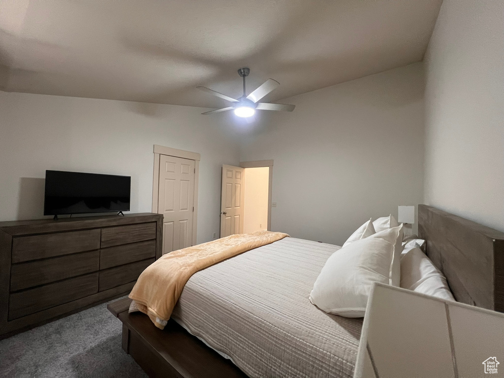 Bedroom featuring a ceiling fan, dark colored carpet, and lofted ceiling