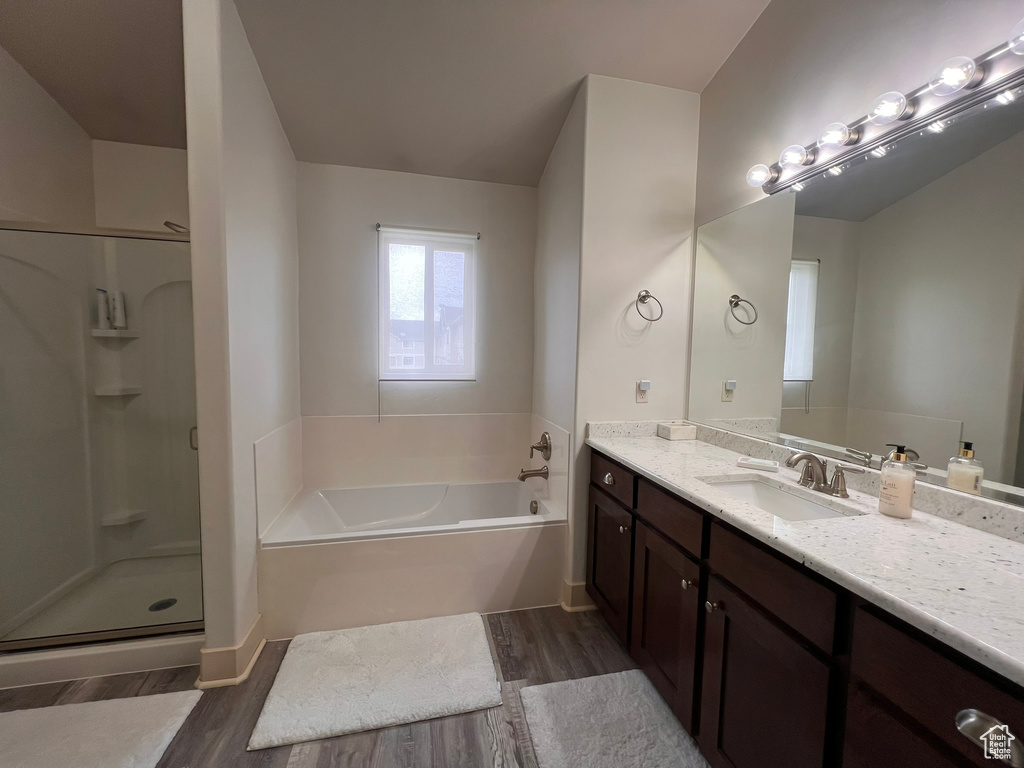 Full bath with a bath, vanity, a shower stall, and wood finished floors