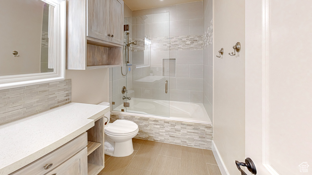 Full bath featuring vanity, tiled shower / bath combo, toilet, and tasteful backsplash