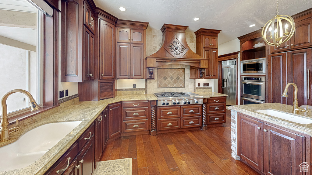Kitchen with a sink, pendant lighting, premium range hood, and stainless steel appliances
