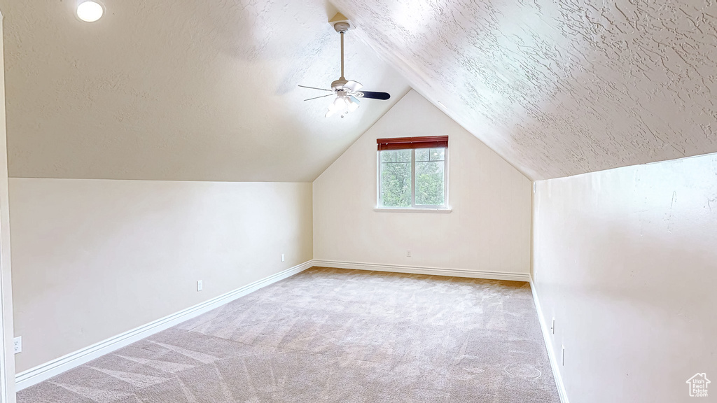 Additional living space with baseboards, carpet, ceiling fan, and vaulted ceiling