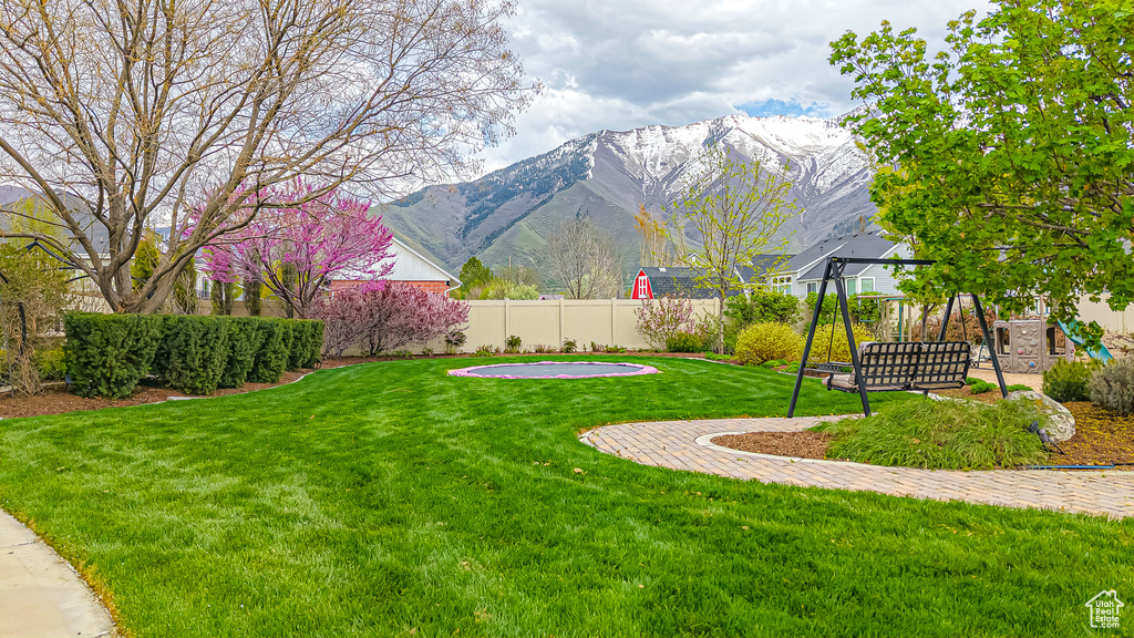 View of yard featuring a playground, fence, and a mountain view
