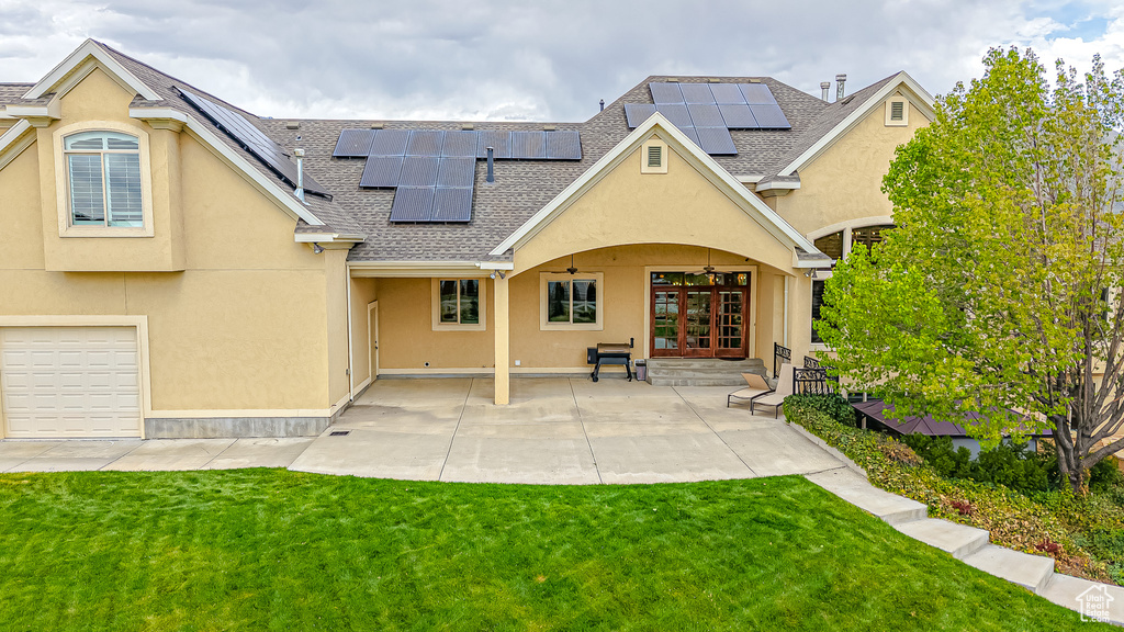 Back of property featuring a lawn, french doors, roof with shingles, and stucco siding