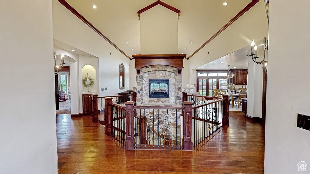 Hallway featuring baseboards, wood-type flooring, an upstairs landing, and a towering ceiling