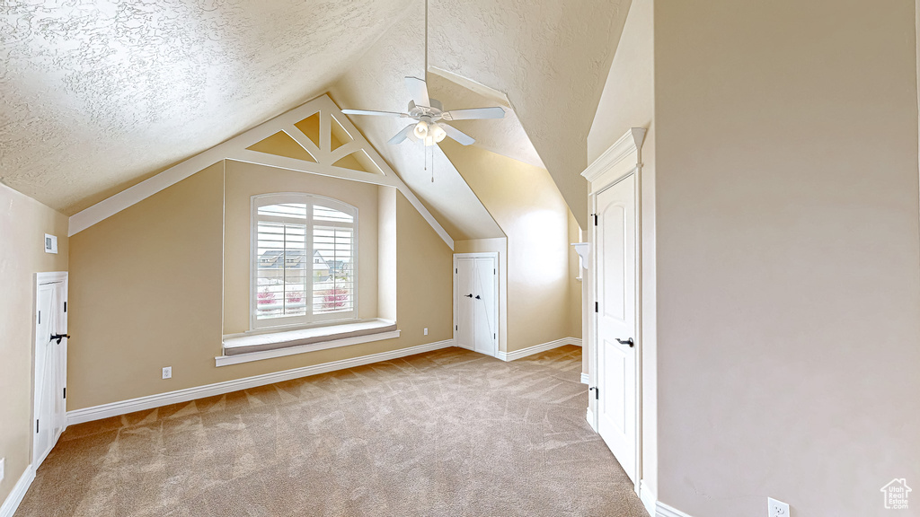 Bonus room with carpet floors, ceiling fan, vaulted ceiling, and a textured ceiling