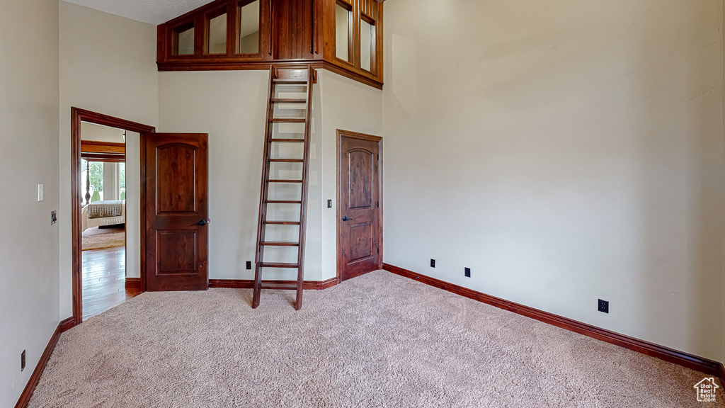 Unfurnished room with carpet floors, baseboards, and a high ceiling