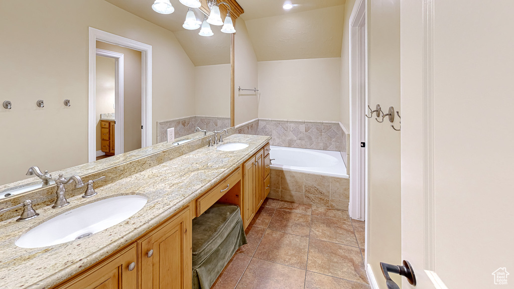 Bathroom featuring double vanity, vaulted ceiling, a sink, and a garden tub