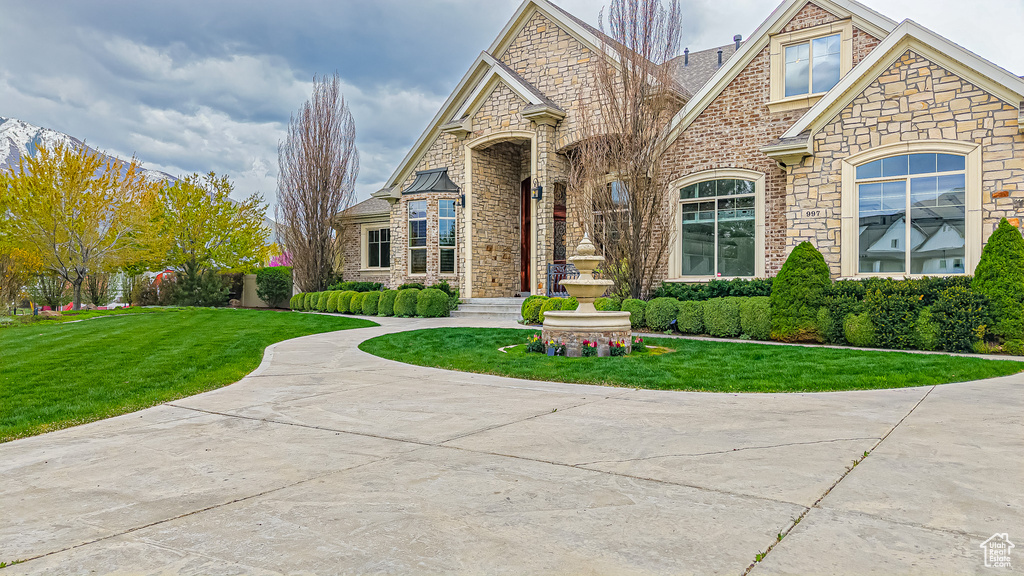 View of front of property featuring brick siding, stone siding, and a front lawn