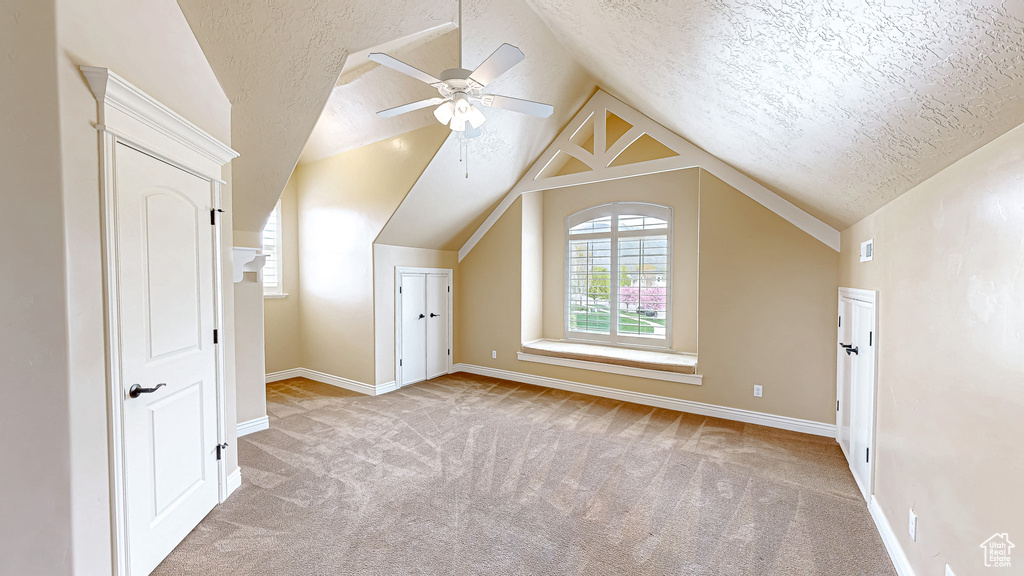 Bonus room featuring a textured ceiling, vaulted ceiling, ceiling fan, and carpet