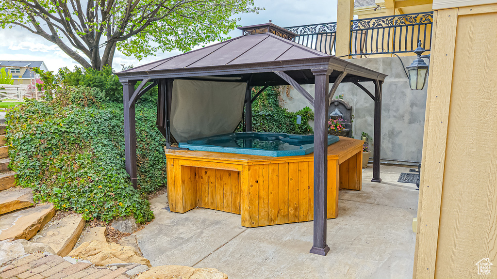 View of patio featuring a hot tub and a gazebo