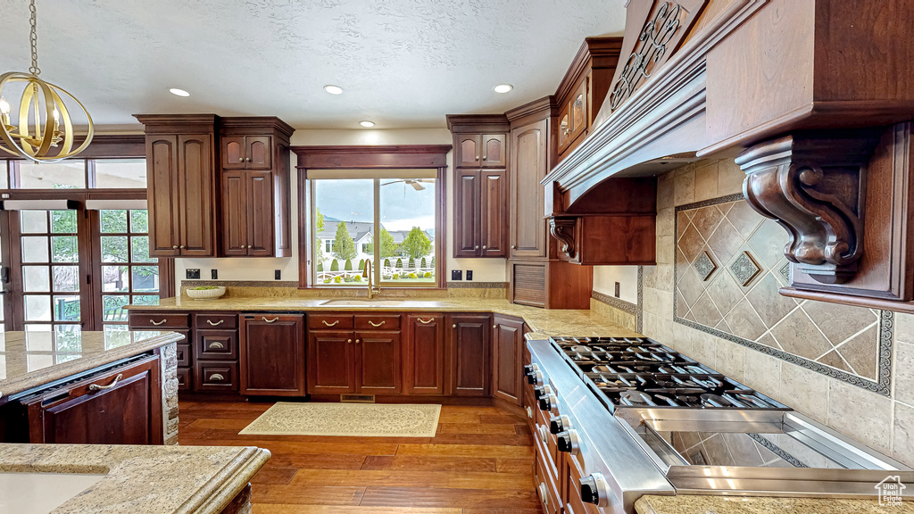Kitchen with dark wood-style floors, recessed lighting, a sink, a notable chandelier, and hanging light fixtures