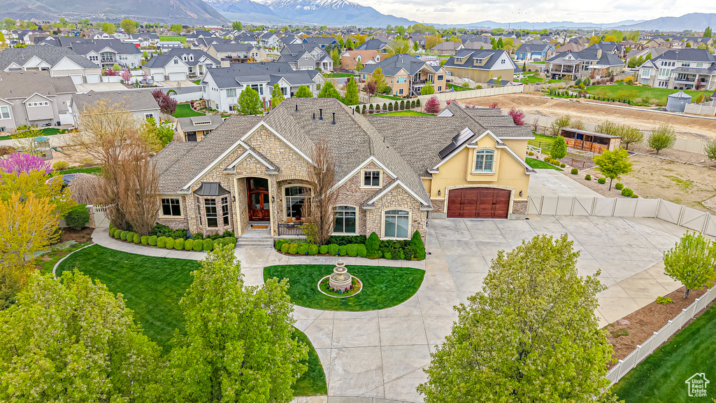 View of front of property with a residential view, a mountain view, stone siding, and concrete driveway