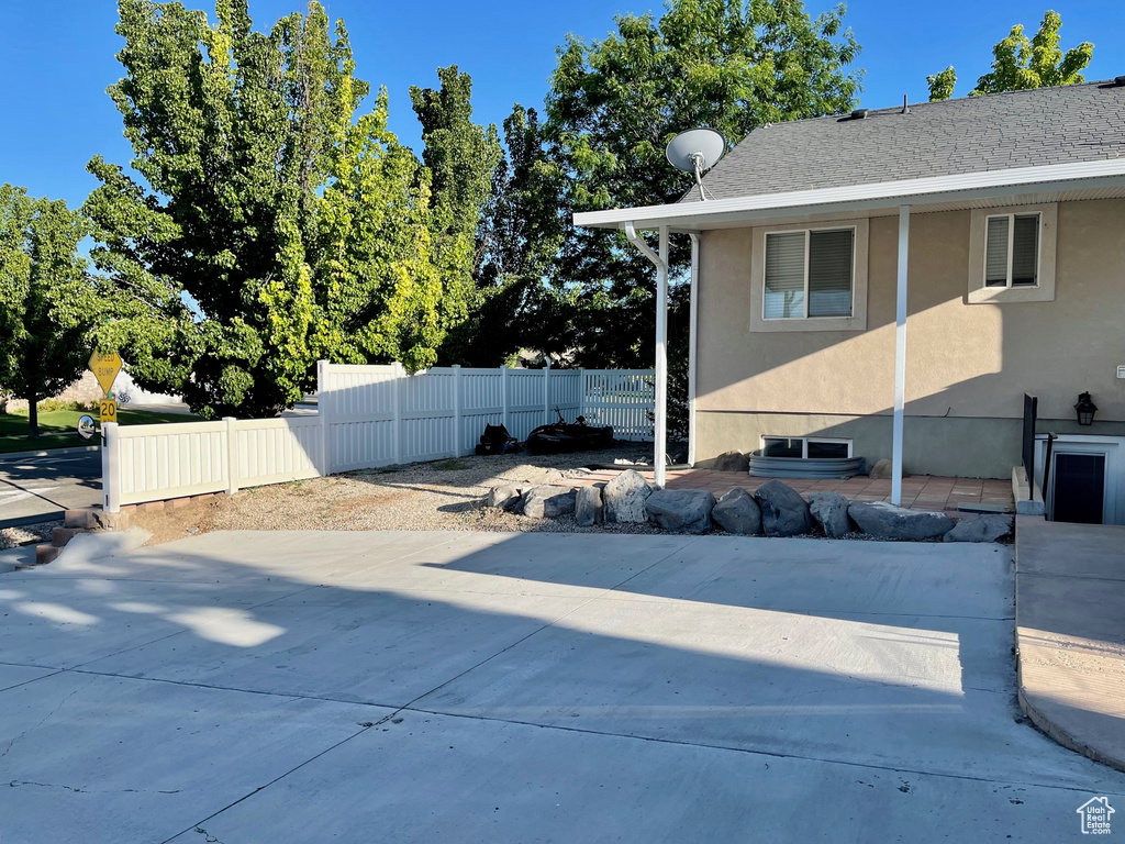 View of property exterior with fence, stucco siding, and a patio area
