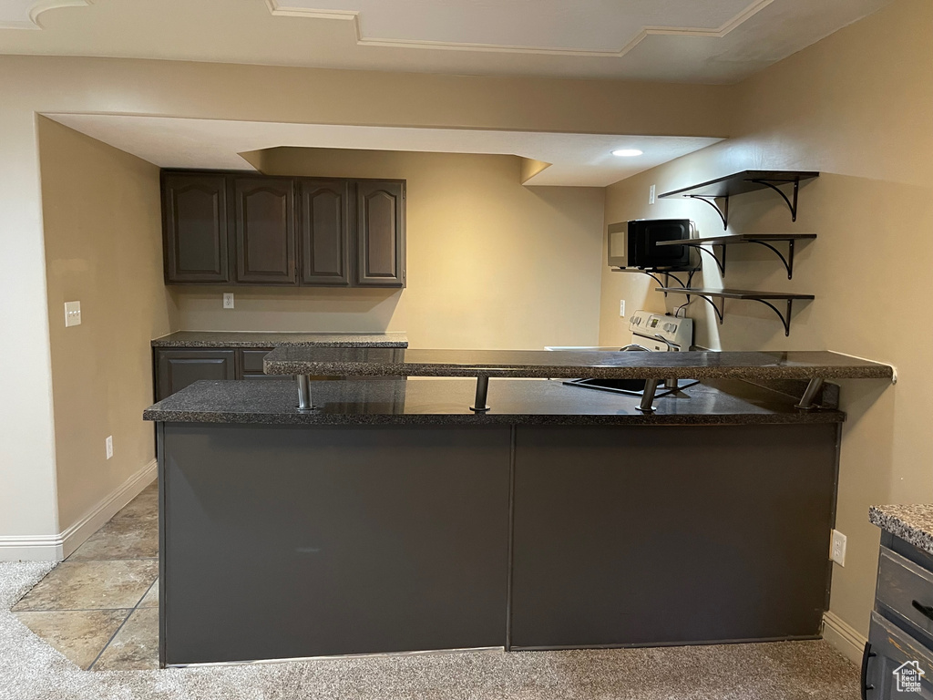 Kitchen featuring baseboards, open shelves, and dark stone countertops