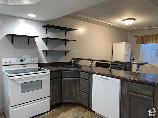 Kitchen featuring visible vents, open shelves, a peninsula, white appliances, and a sink