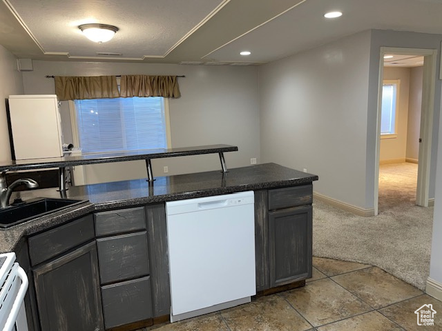Kitchen featuring white dishwasher, a sink, range, recessed lighting, and baseboards