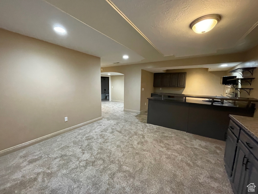Kitchen featuring dark countertops, light carpet, arched walkways, recessed lighting, and baseboards