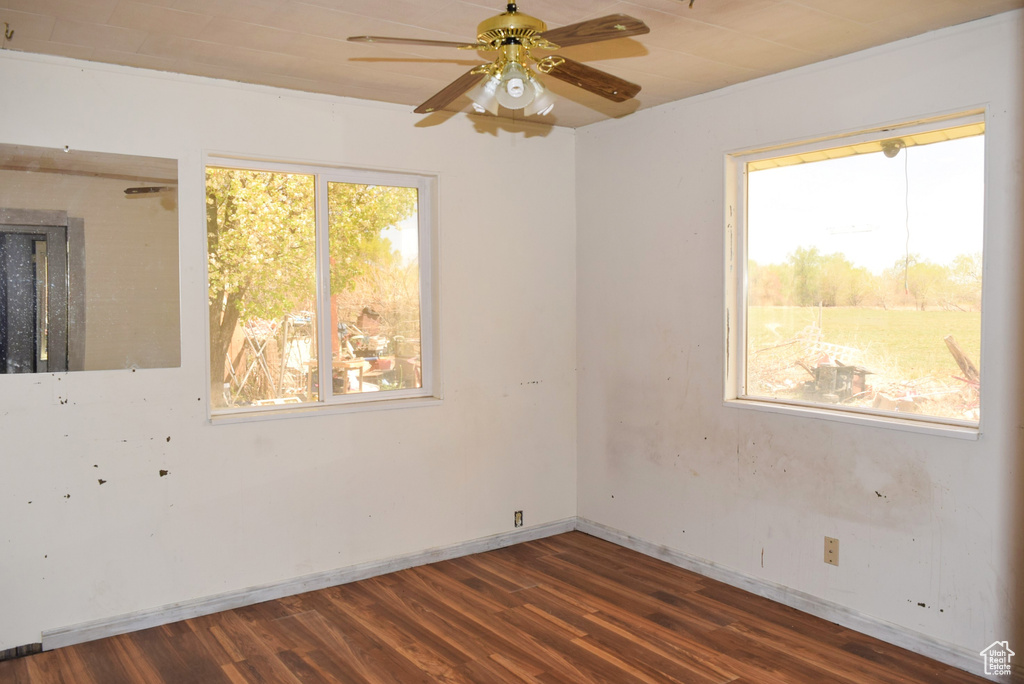 Empty room featuring a ceiling fan and dark wood-style floors