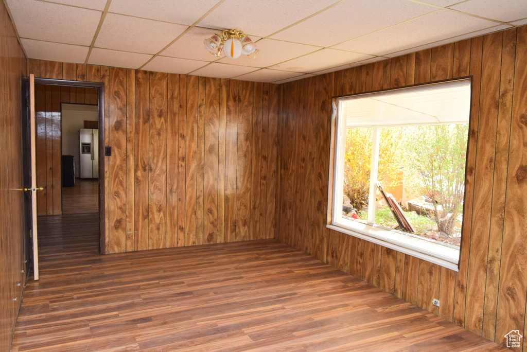 Spare room with wood walls, a paneled ceiling, and wood finished floors