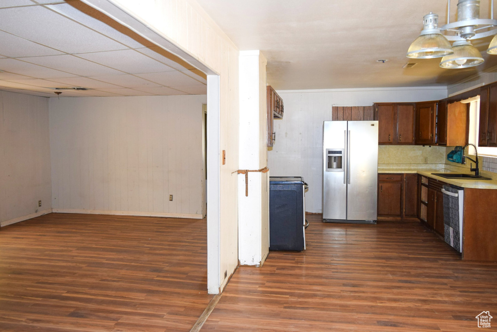 Kitchen featuring a sink, stainless steel fridge with ice dispenser, dishwasher, light countertops, and dark wood-type flooring