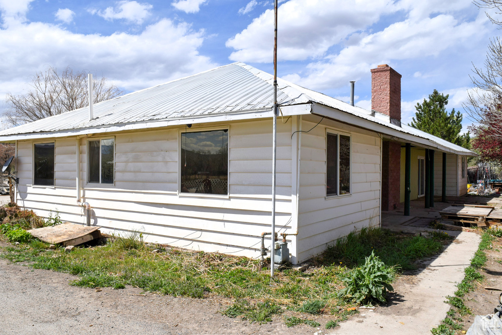 View of home's exterior featuring a chimney and metal roof
