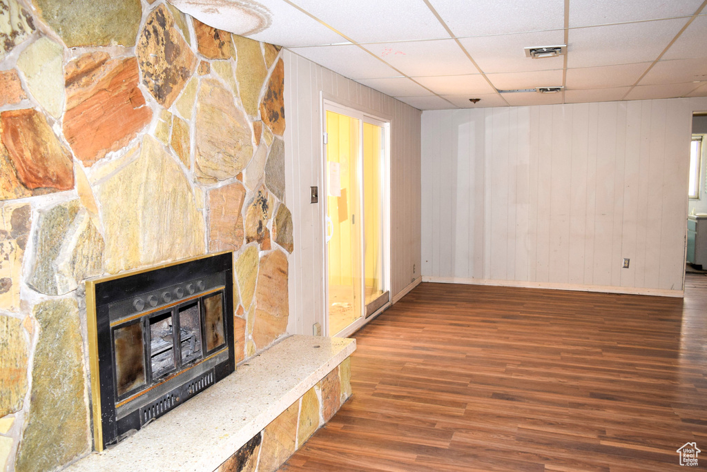 Unfurnished living room featuring visible vents, a drop ceiling, wood finished floors, and a fireplace